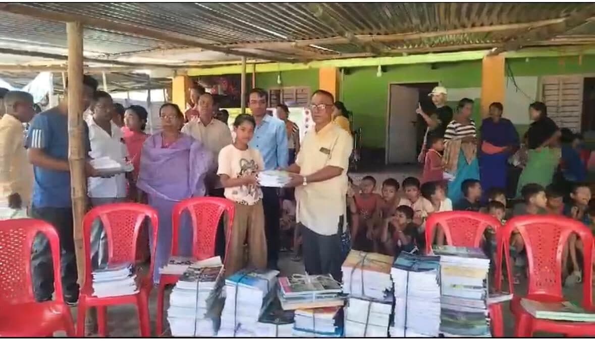 Foundation members distributing stacks of exercise books and stationery to village families